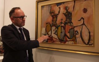 Deutscher and Hackett's Henry Mullholland with John Olsen's work The Bicycle Boys Rejoice, one of the most well known paintings in the James Fairfax collection. (ABC News)